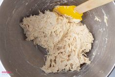 a wooden spoon in a metal bowl filled with food