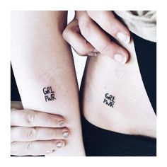 two girls with small tattoos on their arms, one has the word girl power written on it