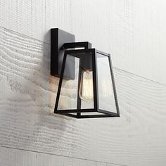 an outdoor wall light on the side of a white wooden wall with a black frame