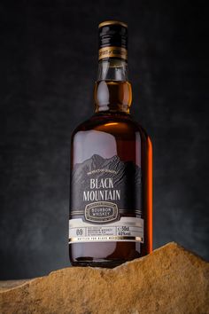 a bottle of black mountain whiskey sitting on top of a rock