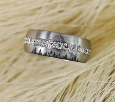 a wedding band with diamonds is shown in front of some fur and white gold feathers