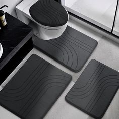 four bathroom mats in various sizes and colors on a counter top next to a toilet