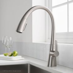 a kitchen faucet with two wine glasses and an apple on the counter next to it