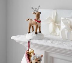 two stuffed animals on top of a mantle next to christmas decorations and presents in front of a fireplace