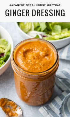 a glass jar filled with ginger dressing next to a bowl of salad