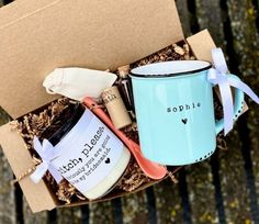 a blue coffee mug sitting inside of a cardboard box next to a spoon and cup