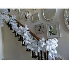 a staircase decorated for christmas with white decorations on the bannister and mirror frames