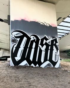 graffiti on the side of a building under a bridge