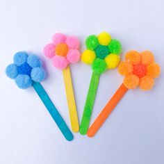 three colorful flower shaped toothbrushes with pom poms on each one's tip