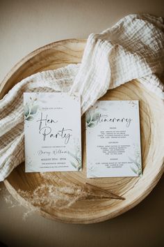 two wedding programs are sitting on a wooden plate with a white cloth draped over it