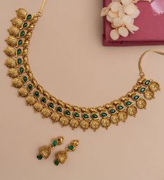 Description: Experience the enchanting charm of our antique coin necklace set, adorned with semi-precious red Kempu stones. Proudly featuring Goddess Lakshmi amidst a row of coins, this gold-plated masterpiece in the Nakshi temple style exudes elegance and auspiciousness, making it an ideal companion for a new bride and elevating every occasion with its divine presence. Details & Specification: Materials used: Brass Alloy with Antique Gold Plating Weight - Necklace- 54.05gm, Earrings- 9.75 gm Length - Necklace-12cm, Earrings-3.5 cm Make it custom: Want to make it a custom Necklace Sets? Sure! Reach out to us at support@tarinika.com and we’ll be happy to make possible modifications at no extra cost. Feel free to write to us on the same email for any other query or concern. Traditional Gold-plated Coin Pendant Necklace, Traditional Gold Plated Coin Pendant Jewelry, Gold Plated Round Temple Necklace, Traditional Gold Coin Necklace For Festivals, Gold Plated Temple Jewelry Necklaces For Rituals, Brass Round Temple Necklace, Traditional Jewelry With Coin Pendant For Rituals, Traditional 22k Gold Necklace With Coin Pendant, Festive Gold Chandbali Emerald Necklace