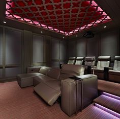 an empty theater with leather recliners and red lighting on the ceiling is shown