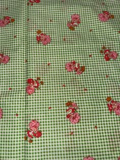 a green and white checkered table cloth with red flowers on it, all over