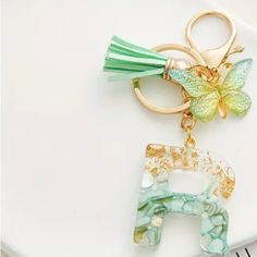 a green and gold keychain with a butterfly on it's back, sitting on top of a white plate