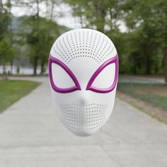 a white mask with purple eyes hanging from it's side in front of a walkway