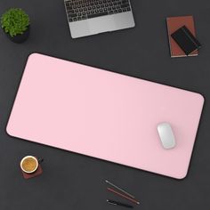 a pink mouse pad sitting on top of a desk next to a laptop and coffee cup