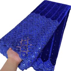 a hand is holding up a blue lace with sequins and beads on it