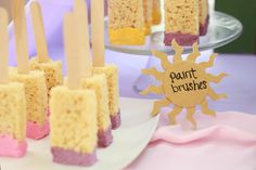 there are many desserts on the table with popsicles in them, and one has a sign that says paintbrushes