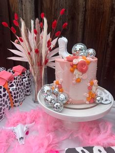 a pink cake sitting on top of a white plate next to feathers and vases