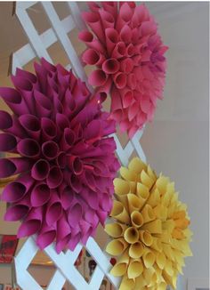 three paper flowers are hanging on a wall