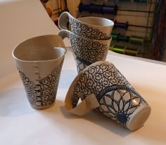 three coffee cups sitting on top of a table next to each other with designs on them