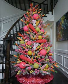 a decorated christmas tree with candy and candies on it's base in front of a spiral staircase