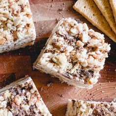 several pieces of cake sitting on top of a wooden cutting board next to crackers