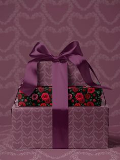 two wrapped gift boxes with purple ribbon and roses on them, one has a bow