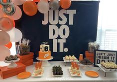 an orange and white dessert table with balloons