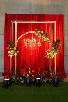 a red backdrop with chandelier and flowers on it, along with potted plants