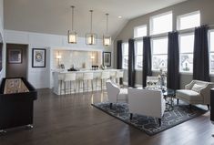 a living room filled with white furniture and lots of windows next to a bar area