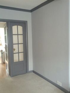 an empty room with a gray door and white walls