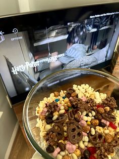 a glass bowl filled with cereal on top of a table next to a laptop computer