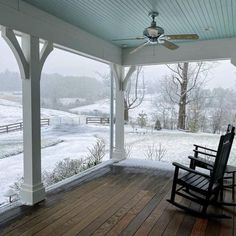 a rocking chair sitting on top of a wooden porch next to a snow covered field