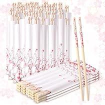 several white chopsticks are lined up next to each other with pink flowers in the background