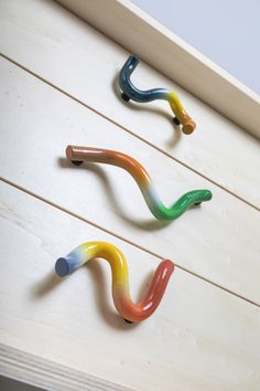 three different colored toothbrushes sitting on top of a wooden shelf