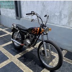 a motorcycle with flames painted on it parked in front of a gray wall and tiled floor