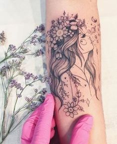 a woman's arm with a tattoo on it and flowers in her hair, next to some lavenders