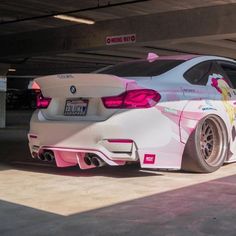 a white car with pink accents parked in a parking garage