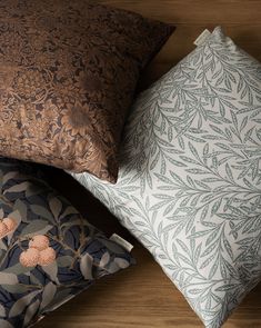 four decorative pillows stacked on top of each other in various colors and patterns, one is brown the other is blue