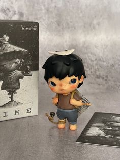 a small figurine is next to a book and an old photo on the table