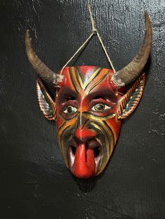 a red mask with horns hanging on a wall