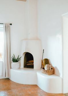 a living room with white walls and wood floors is furnished with a fireplace in the center