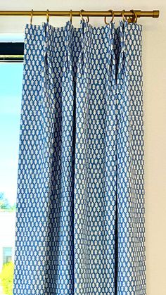 the curtains are hanging in front of an open window with blue and white patterns on them