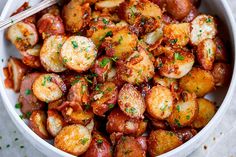 a close up of a bowl of food with potatoes and parsley on the side