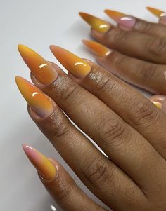 a woman's hand with orange and yellow nail polishes on her nails, against a white background