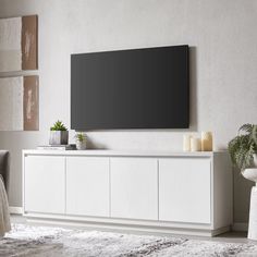 a large flat screen tv mounted to the side of a white cabinet in a living room