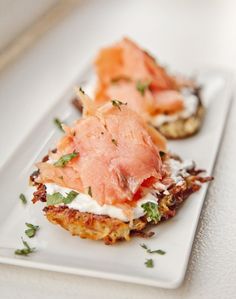 two crab cakes with cream cheese and parsley on top are sitting on a white plate