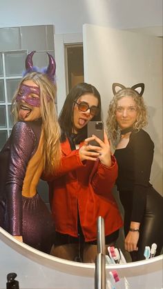 three women dressed up in costumes taking a selfie