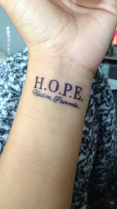 a woman's wrist tattoo with the word hope written in cursive font